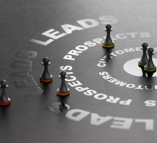 A black surface features concentric circles labeled "LEADS," "PROSPECTS," and "CUSTOMERS." Chess pawns of various colors are placed along these circles, representing different stages of a sales funnel or customer journey.